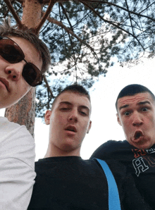 three young men are posing for a picture with one wearing a black shirt with the letter a on it