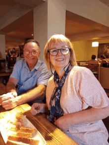 a man and woman sit at a table with a plate of food in front of them