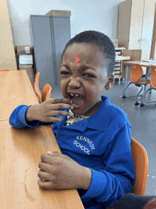 a young boy wearing a blue kennedy school shirt making a funny face