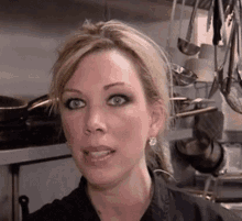 a close up of a woman 's face in a kitchen with pots and pans hanging from the ceiling .