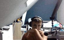 a shirtless boy wearing headphones and a microphone in a bedroom