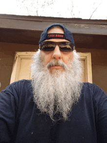 a man with a beard wears a plaza bingo hat and sunglasses