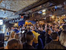 a crowd of people are gathered in a bar with a sign on the wall that says ' miller '