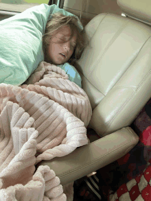 a little girl is sleeping in a car seat