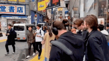 a group of people are walking down a street in front of a store with chinese writing on it .