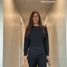 a woman in a black shirt is standing in a hallway with kat kanada written on the bottom