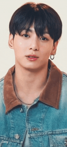 a close up of a man wearing a denim jacket and earrings