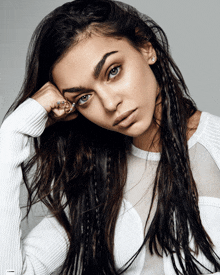 a woman with braids in her hair is wearing a white top