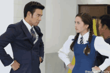 a man in a suit and tie stands next to a girl in a school uniform