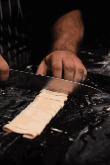 a person is cutting a piece of pasta with a large knife