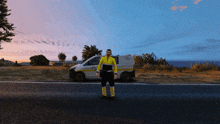 a man in a yellow jacket stands in front of a van that says ' ambulance ' on the side