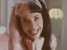 a woman with half pink and half black hair is smiling and looking at the camera