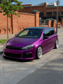 a purple car is parked on a sidewalk in front of a brick wall