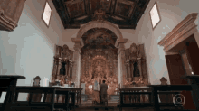 a man in a suit stands in front of an altar in a church with a globe in the corner