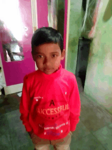 a young boy wears a red sweater that says successful