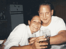 a man and a woman are posing for a picture while holding glasses