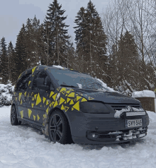 a black van with yellow triangles on the side is parked in the snow