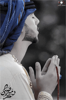 a man wearing a blue head scarf praying with the word ramadan written on the bottom