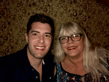 a man and a woman posing for a picture in front of a wall with circles on it