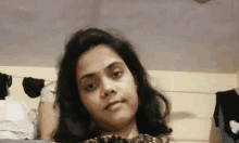 a woman is sitting on a bed looking at the camera and making a funny face .