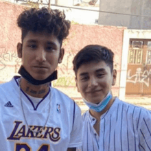 a man wearing a lakers jersey poses for a picture with another man