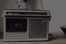 an old radio and cassette player are sitting on a wooden table .