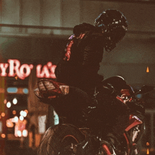 a person riding a motorcycle in front of a sign that says ' roy 's ' on it