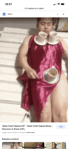 a man in a pink dress is laying on a table with two cups of coffee