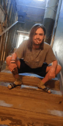 a man with long hair is squatting down on a set of stairs with a cigarette in his mouth