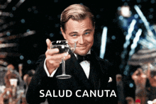 a man in a tuxedo holds up a glass of wine with salud canuta written on the bottom