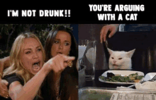 two women are sitting at a table with a plate of food and a cat behind them .