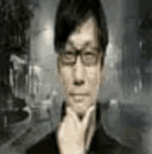 a man wearing glasses is holding his hand to his chin and looking at the camera .