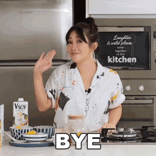 a woman in a kitchen with a sign that says " laughter and wild blues come together in this kitchen "