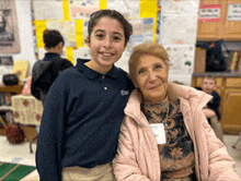 a girl wearing a shirt that says ' liberty school ' on it poses for a picture with an older woman