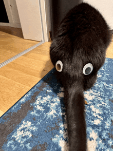 a black cat with googly eyes on its back