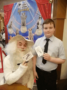 a man with a white beard is standing next to a boy in front of a sign that says " teatp koшек "