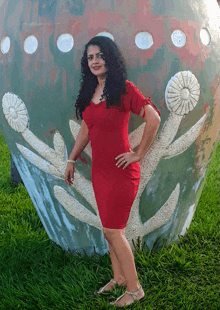 a woman in a red dress is standing in front of a sculpture