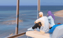 a man and a woman sitting on a couch looking out a window at the ocean