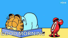 garfield is laying in a box next to a red alarm clock that says " good morning "