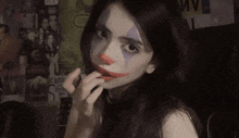 a woman with a clown makeup on her face looks at the camera