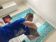 a boy wearing a blue adidas shirt holds a pillow over his head