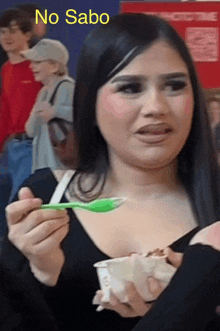 a woman is eating ice cream with a green spoon and the words no sabo on the bottom