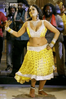 a woman in a yellow dress is dancing in front of a group of people