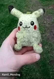 a person is holding a stuffed animal that looks like a pikachu made out of rice .