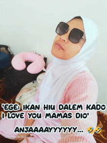 a woman wearing sunglasses and a hijab is sitting on a bed