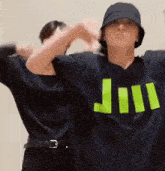 a man wearing a hat and a black shirt with the letter j on it is dancing with another man .