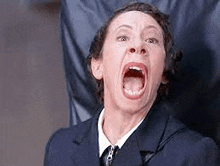 a woman in a suit and tie is making a funny face with her mouth wide open .