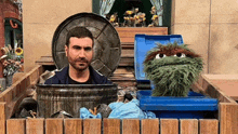 a man is standing in a trash can next to a sesame street puppet