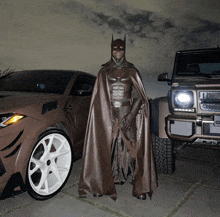 a man in a batman costume stands next to a car