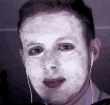 a man with a white mask on his face is wearing headphones and making a funny face .